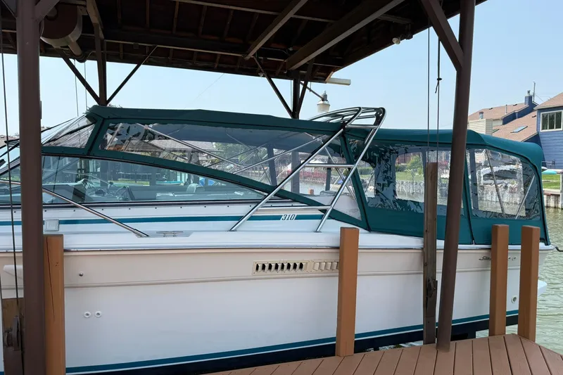 Slide: The Image of 1994 Sea Ray 310 Amberjack docked under a covered marina, featuring teal canvas covers. - 6