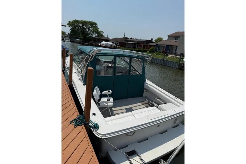 Slide: The Image of 1994 Sea Ray 310 Amberjack docked, featuring a spacious deck and teal canopy. - 7