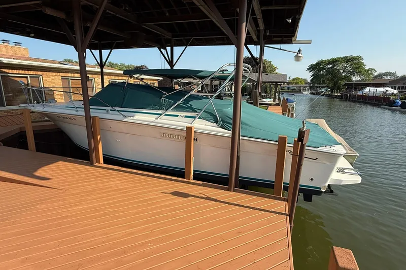 Slide: The Image of 1994 Sea Ray 310 Amberjack docked under a wooden canopy on a sunny day. - 8