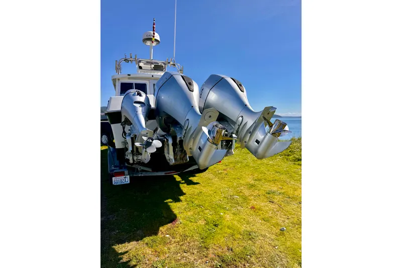 Slide: The Image of 2001 Skagit Orcas 27XLC boat with dual outboard motors on grassy shore. - 21
