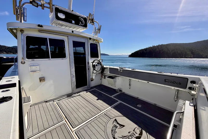 Slide: The Image of 2001 Skagit Orcas 27XLC boat with spacious deck, scenic water view, and clear blue sky. - 7