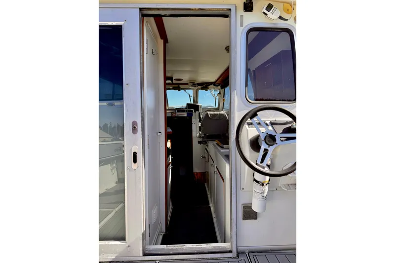 Slide: The Image of Interior view of 2001 Skagit Orcas 27XLC boat, featuring steering wheel and cabin entrance. - 9