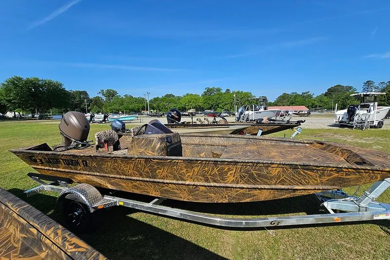 Slide: The Image of 2026 G3 Gator Tough 17 SC boat on trailer, camo design, parked outdoors. - 6