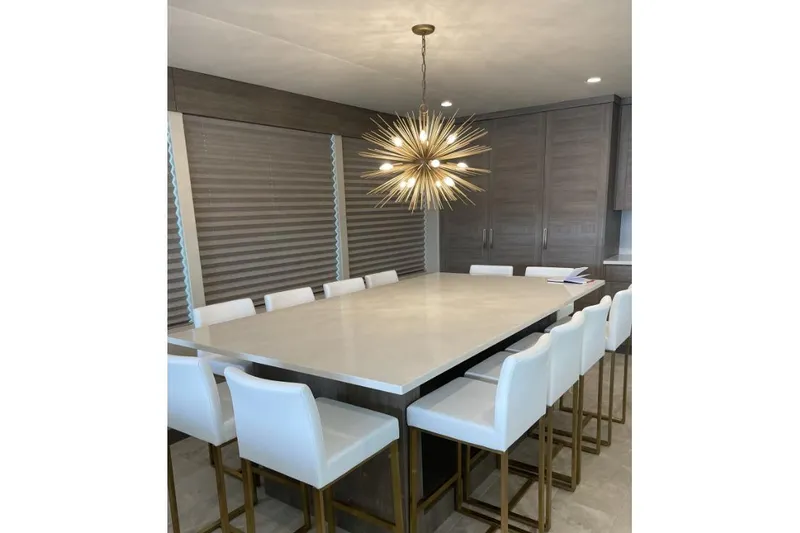 Slide: The Image of Modern dining area with large table, white chairs, and a striking starburst chandelier. - 14