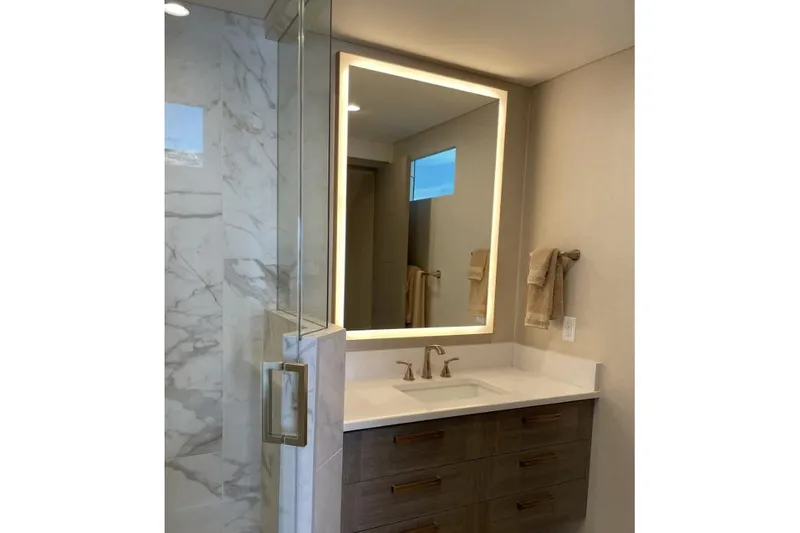 Slide: The Image of Modern bathroom with illuminated mirror, marble shower, and wooden vanity. - 4