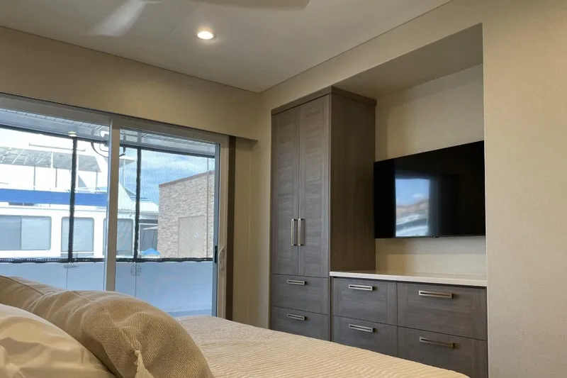 Slide: The Image of Modern bedroom interior with large window, sleek cabinetry, and wall-mounted TV in Adonia model. - 5