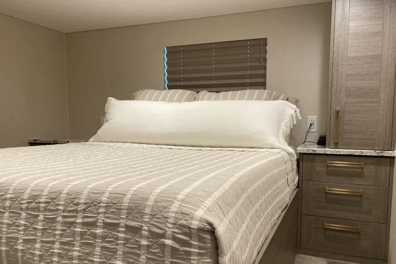 Slide: The Image of Cozy bedroom in Adonia Max'd Out Trip 7A, featuring a neatly made bed and wooden cabinetry. - 8