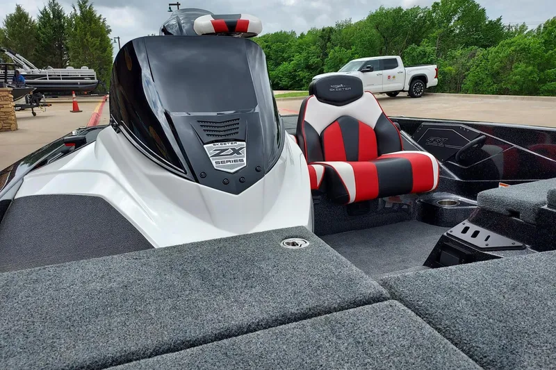 Slide: The Image of 2021 Skeeter ZX200 boat interior with red and black seating, parked outdoors. - 6