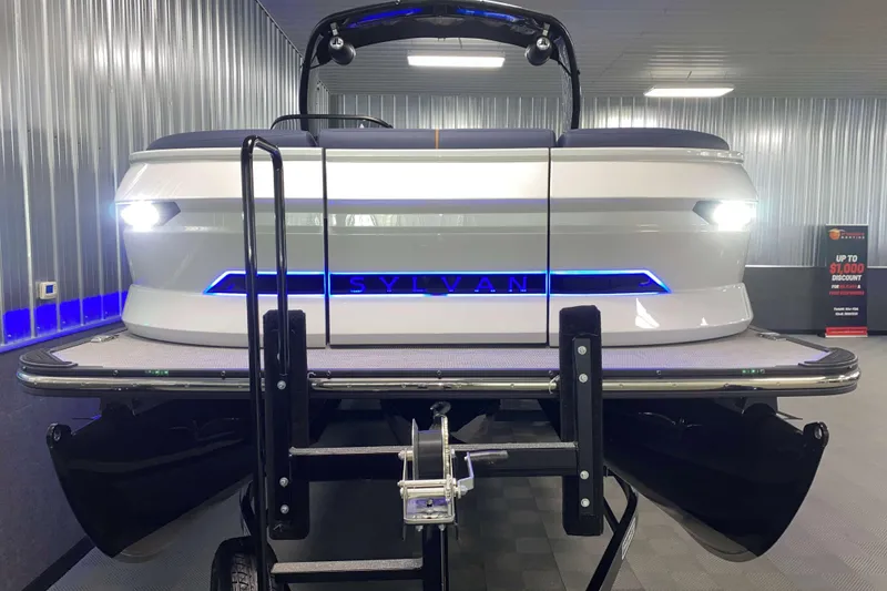 Slide: The Image of 2025 Sylvan M3 DLZ DH Tritoon boat in showroom with illuminated logo and sleek design. - 22