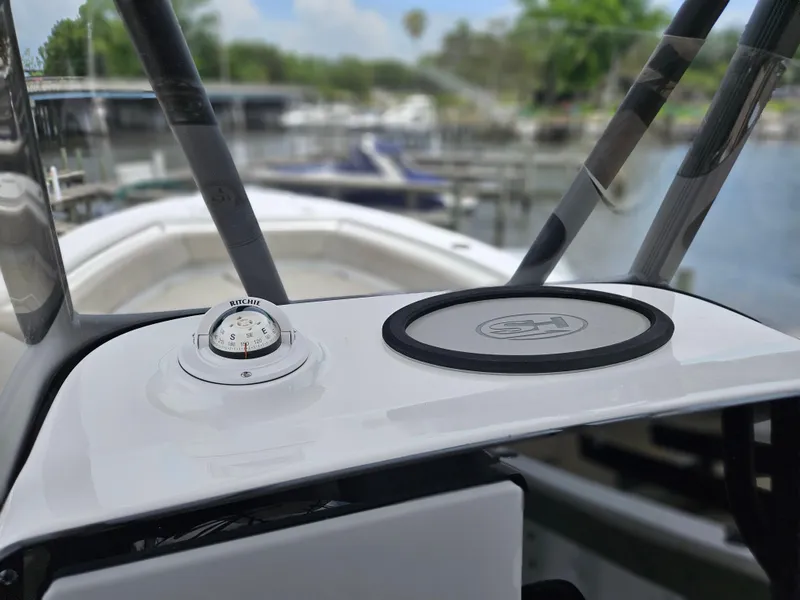Slide: The Image of 2025 Sea Hunt Ultra 219 boat dashboard with compass, docked in marina. - 12
