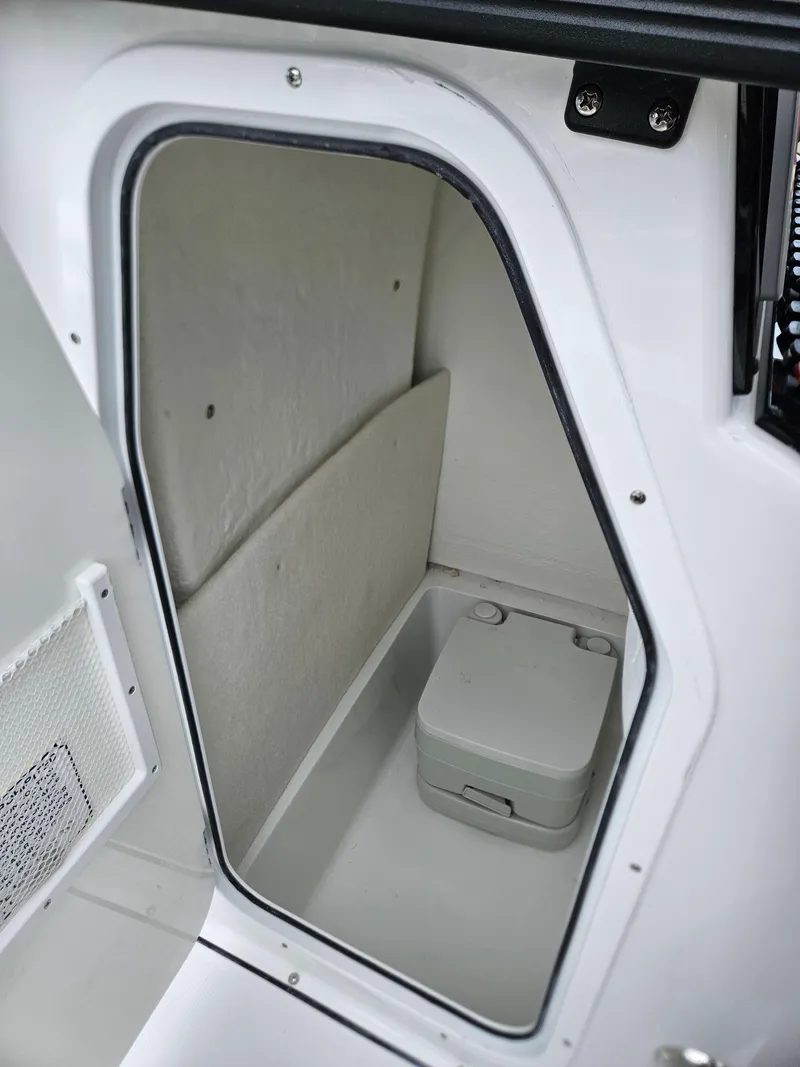 Slide: The Image of 2025 Sea Hunt Ultra 219 boat interior storage compartment with portable toilet. - 20