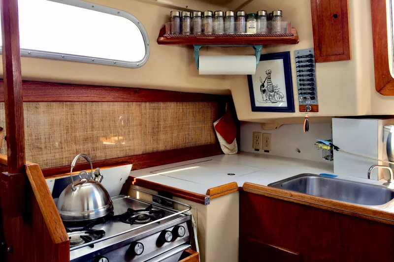 Slide: The Image of 1971 Pearson Competitor sailboat kitchen with stove, kettle, spice rack, and sink. - 9