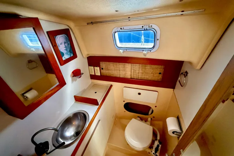 Slide: The Image of 1971 Pearson Competitor yacht bathroom with sink, toilet, mirror, and porthole window. - 14