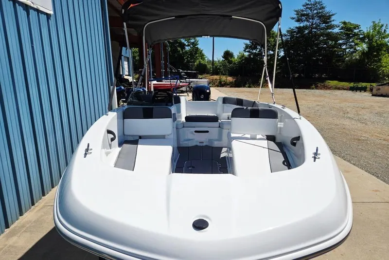 Slide: The Image of 2026 Tahoe T18 boat with canopy, docked near a blue building. - 12
