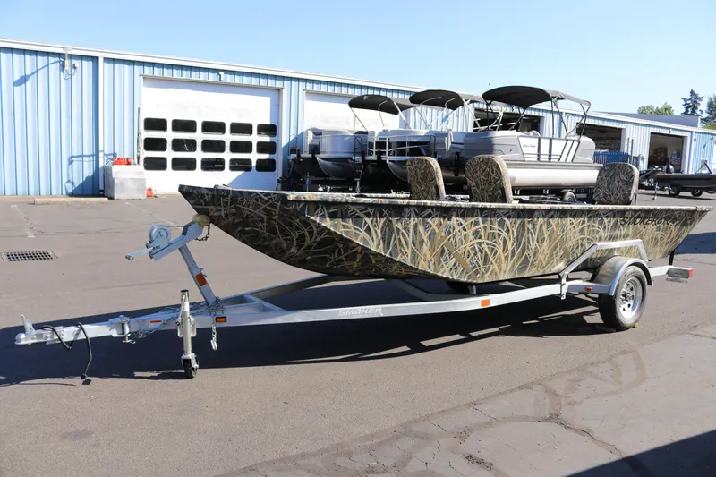Slide: The Image of 2026 Smoker Craft Sportsman 1660 boat on trailer, camo design, parked outside warehouse. - 3