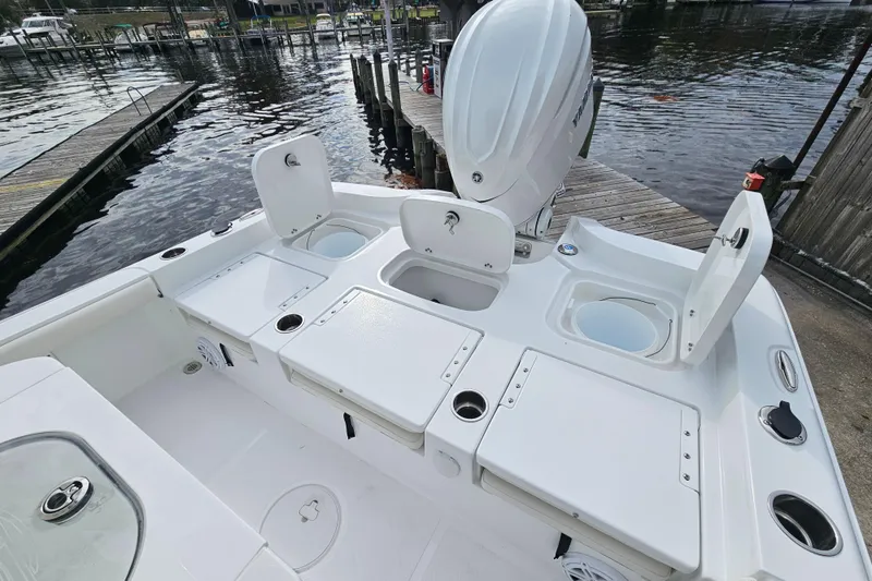 Slide: The Image of 2026 Sea Hunt BX 25 FS boat with open storage compartments, docked by the water. - 9