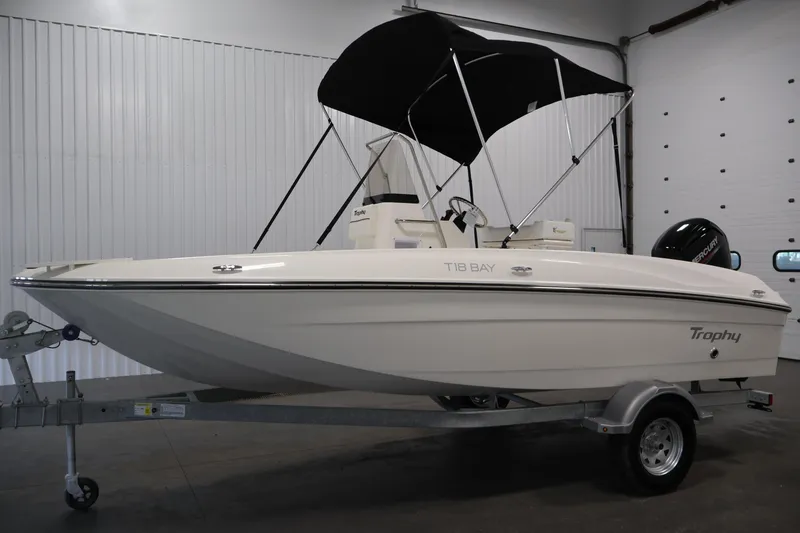 Slide: The Image of 2026 Bayliner Trophy T18 boat with canopy on trailer in indoor setting. - 14