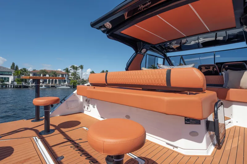 Slide: The Image of Luxurious 2026 Hanover 387 yacht interior with orange seating, docked by waterfront homes. - 12