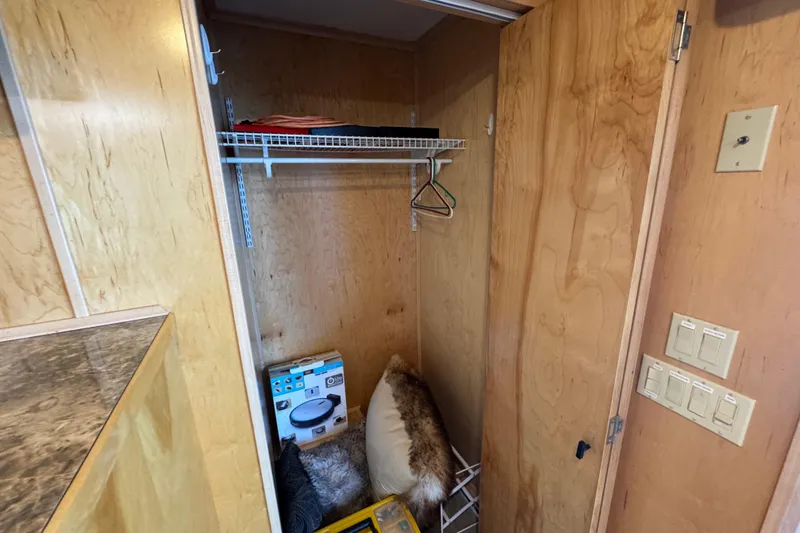 Slide: The Image of Wooden closet interior with shelves, hangers, and household items in a 2004 Starlite 65x16 model. - 60