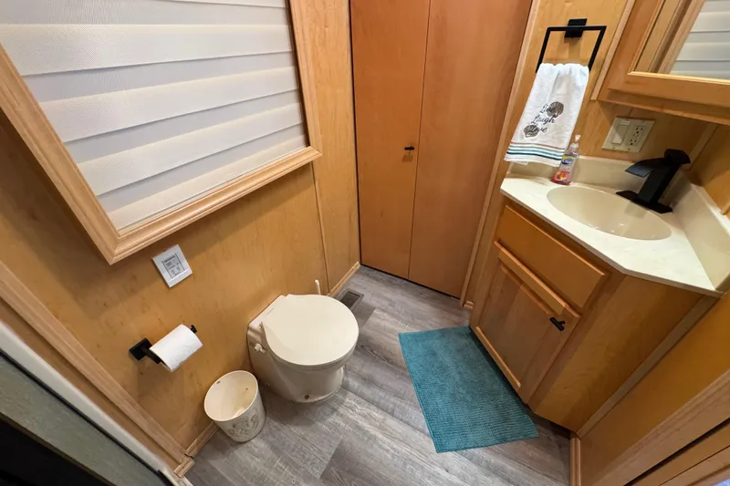 Slide: The Image of Compact bathroom in 2004 Starlite 65x16, featuring toilet, sink, and wooden cabinetry. - 65