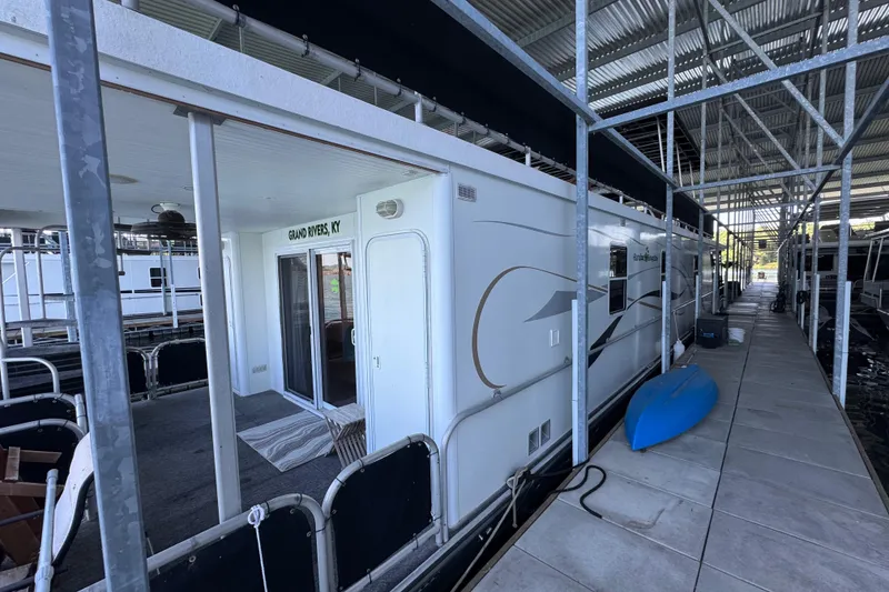 Slide: The Image of Houseboat docked in marina, Starlite 65x16 model, 2004, with blue kayak nearby. - 7