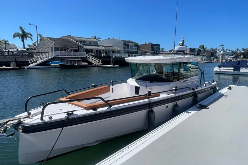 The Image of 2022 Axopar Brabus 28 Cabin boat docked in a scenic marina setting. - 0