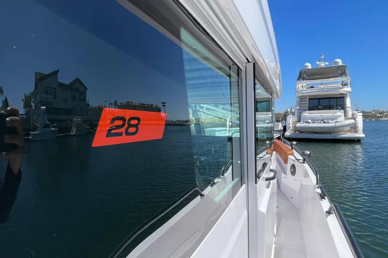 Slide: The Image of 2022 Axopar Brabus 28 Cabin boat docked near luxury yacht in marina. - 15