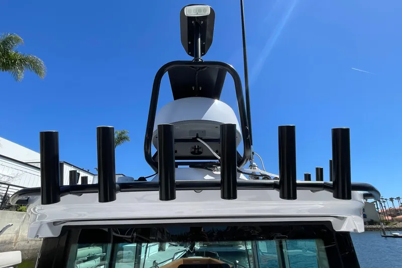 Slide: The Image of 2022 Axopar Brabus 28 Cabin boat with rod holders and radar, under clear blue sky. - 19