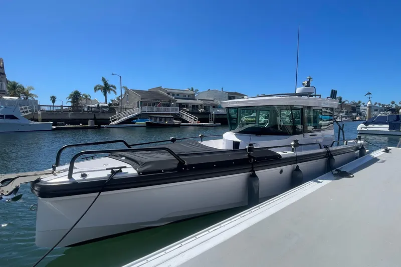 Slide: The Image of 2022 Axopar Brabus 28 Cabin boat docked in a sunny marina setting. - 2