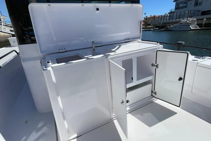 Slide: The Image of 2022 Axopar Brabus 28 Cabin boat with open storage compartments and sink. - 22