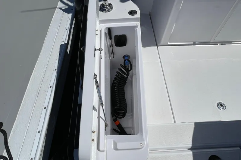 Slide: The Image of Storage compartment on 2022 Axopar Brabus 28 Cabin boat, featuring coiled hose. - 51