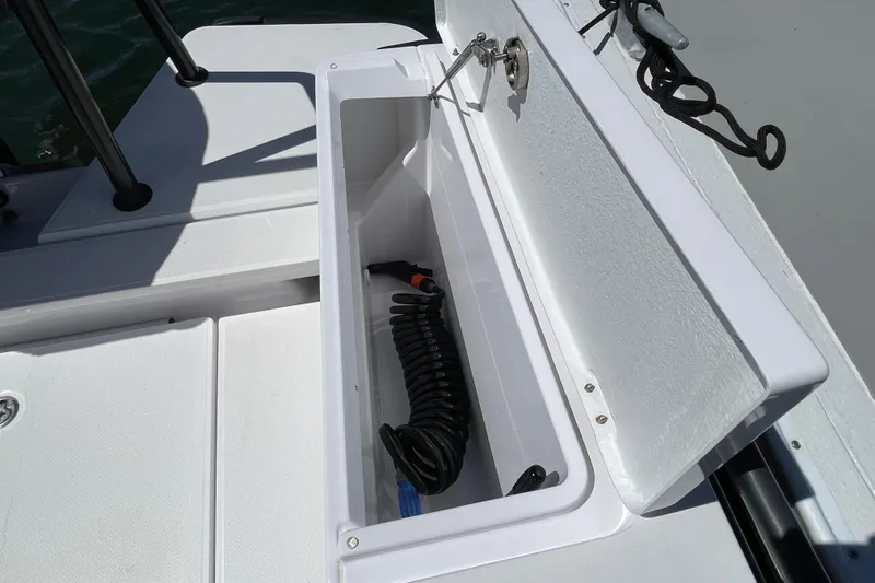 Slide: The Image of Storage compartment on 2022 Axopar Brabus 28 Cabin boat, featuring coiled hose. - 52