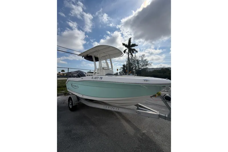 The Image of 2021 Robalo R180 Center Console boat on trailer under cloudy sky. - 0