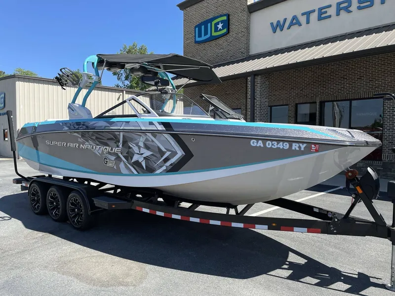 The Image of 2015 Nautique G25 boat on trailer outside watersport store. - 1