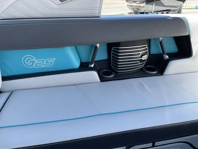 Slide: The Image of Interior of a 2015 Nautique G25 boat with blue and white seating. - 13