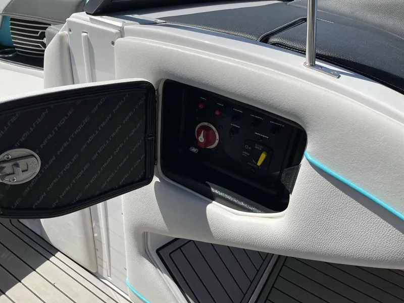 Slide: The Image of 2015 Nautique G25 boat control panel with open compartment. - 24