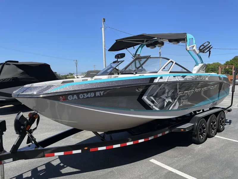 Slide: The Image of 2015 Nautique G25 boat on trailer, blue and black, parked outdoors. - 4