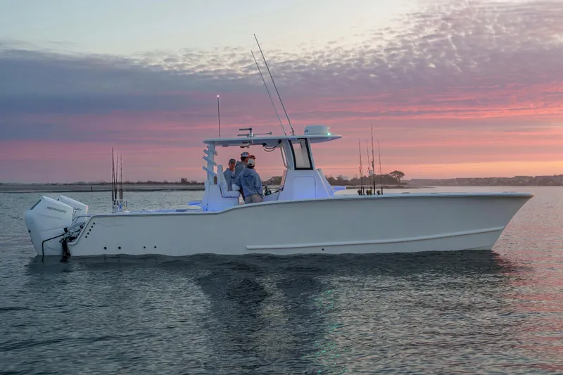 Slide: The Image of 2026 Tideline 365 Offshore boat on calm water at sunset, featuring fishing rods and Mercury engine. - 49