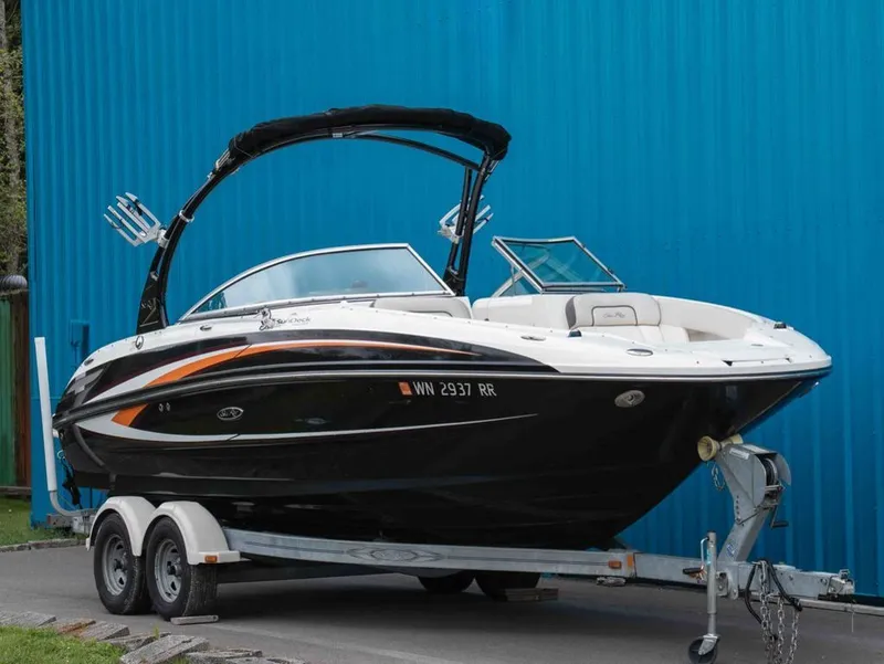 The Image of 2012 Sea Ray 240 Sundeck on trailer against blue background. - 1