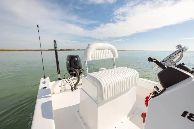 Slide: The Image of Privateer 18 Retriever 2026 boat interior with steering console and seating on calm water. - 7