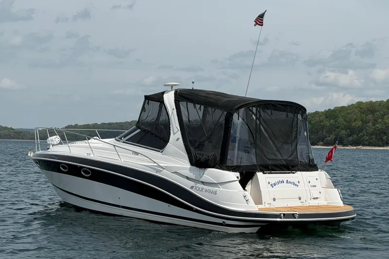 Slide: The Image of 2009 Four Winns V358 boat on water with American flag, forested shoreline in background. - 4