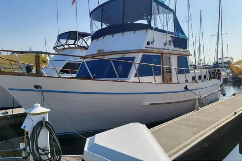 The Image of 1981 Marine Trader Trunk Cabin yacht docked at marina, featuring classic design and blue accents. - 1