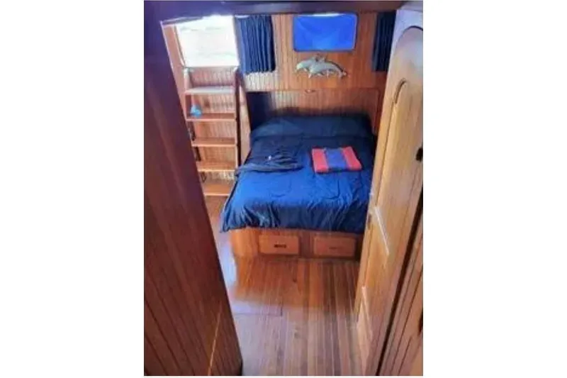 Slide: The Image of Cozy cabin interior of 1981 Marine Trader Trunk Cabin with wooden furnishings and a neatly made bed. - 10