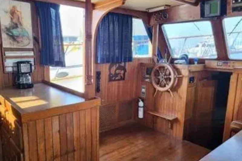 Slide: The Image of 1981 Marine Trader Trunk Cabin interior with wooden helm, nautical decor, and coffee maker. - 12