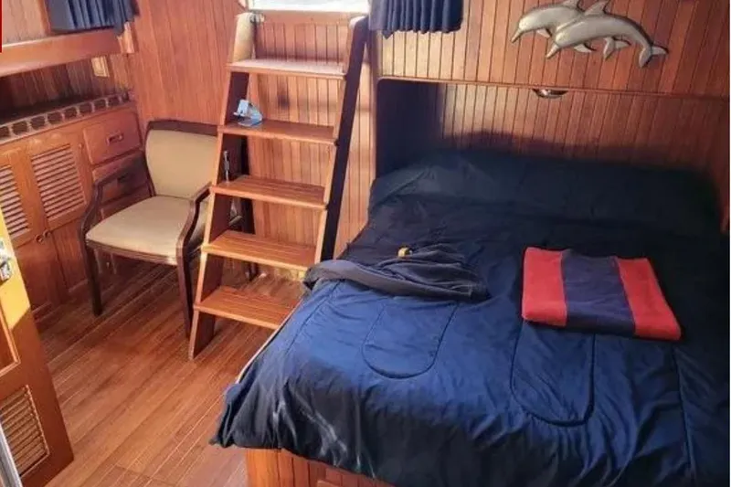 Slide: The Image of 1981 Marine Trader Trunk Cabin interior with wooden decor and cozy bed. - 3