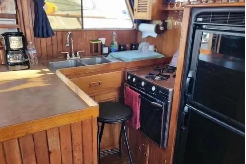 Slide: The Image of 1981 Marine Trader Trunk Cabin kitchen with stove, sink, and refrigerator. Cozy wooden interior. - 5