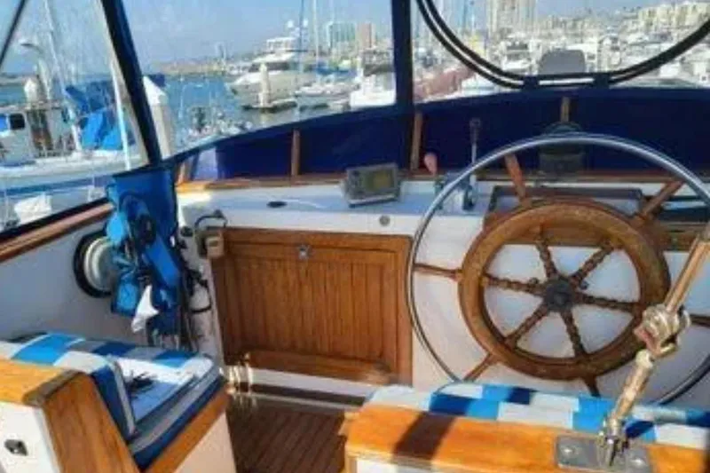 Slide: The Image of 1981 Marine Trader Trunk Cabin helm with wooden wheel, nautical instruments, and marina view. - 9