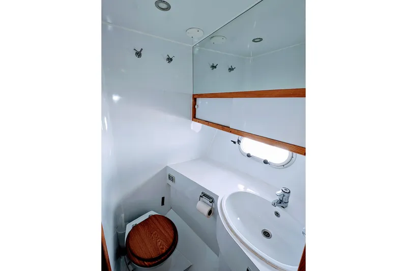 Slide: The Image of Compact bathroom in 1990 Neptunus Sedan 148 yacht, featuring wooden accents and a porthole window. - 23