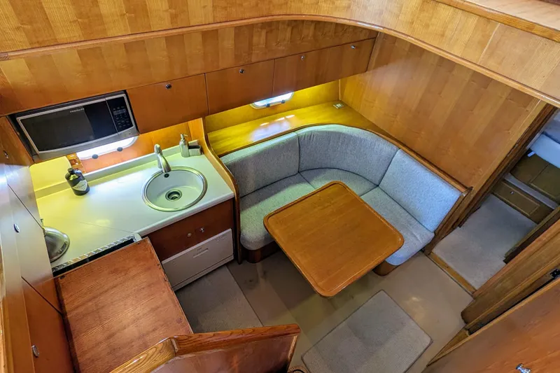 Slide: The Image of Cozy 1990 Neptunus Sedan 148 yacht interior with kitchenette and dining area. - 6
