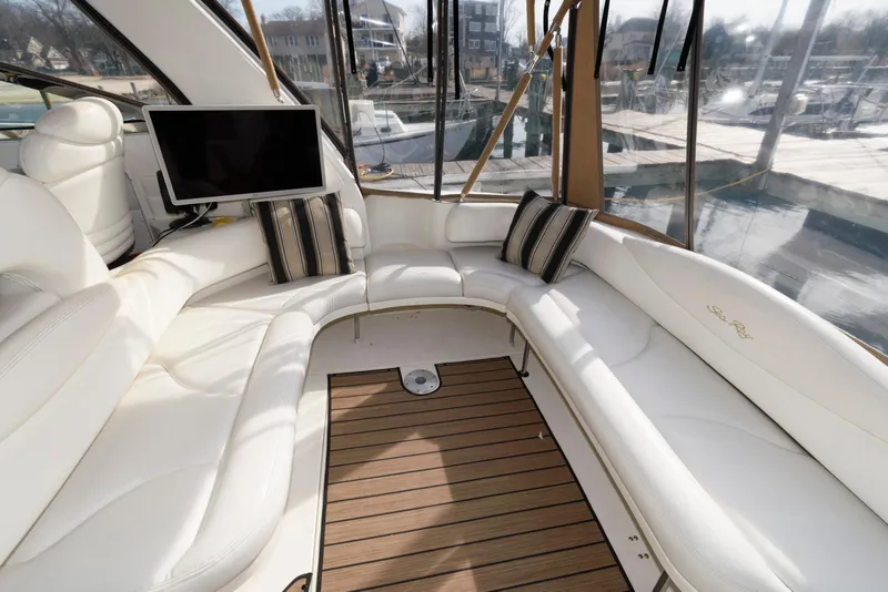 Slide: The Image of 1999 Sea Ray 380 Sundancer interior with white seating, wood flooring, and a mounted TV. - 11